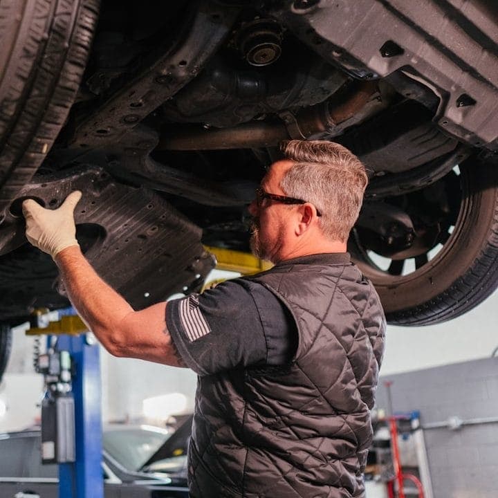 Technician working beneath a vehicle on a ramp