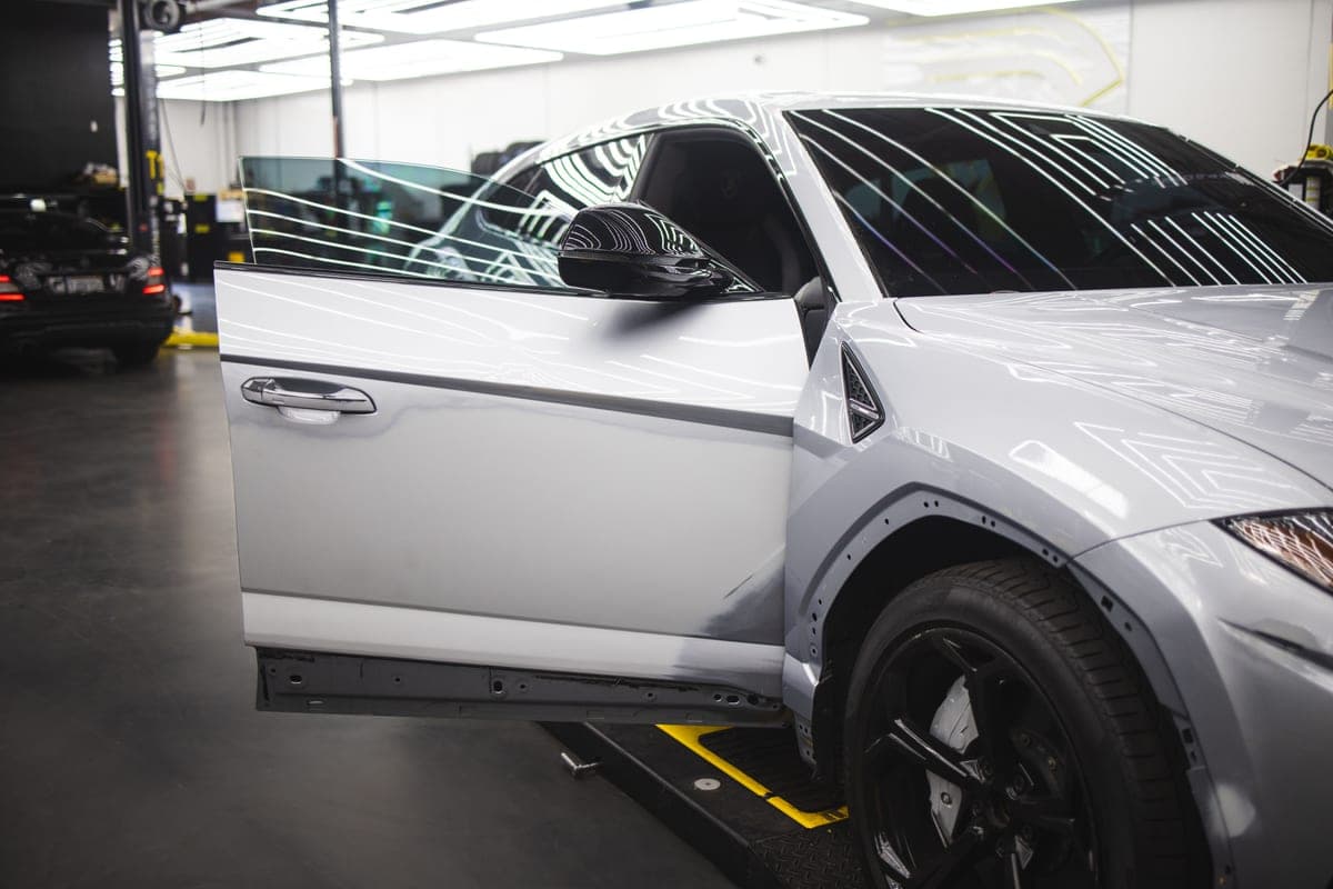 Car with its door open in a bodyshop bay