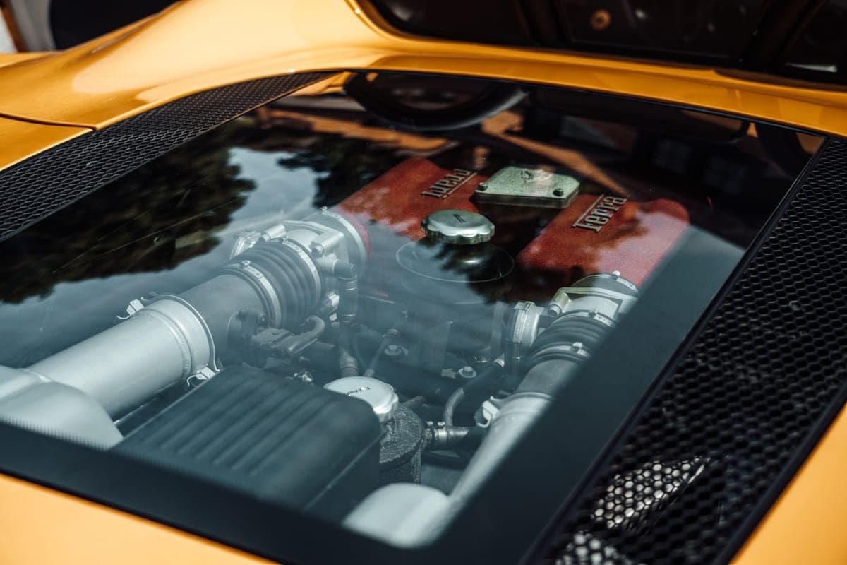 Engine of a yellow supercar seen through the rear glass